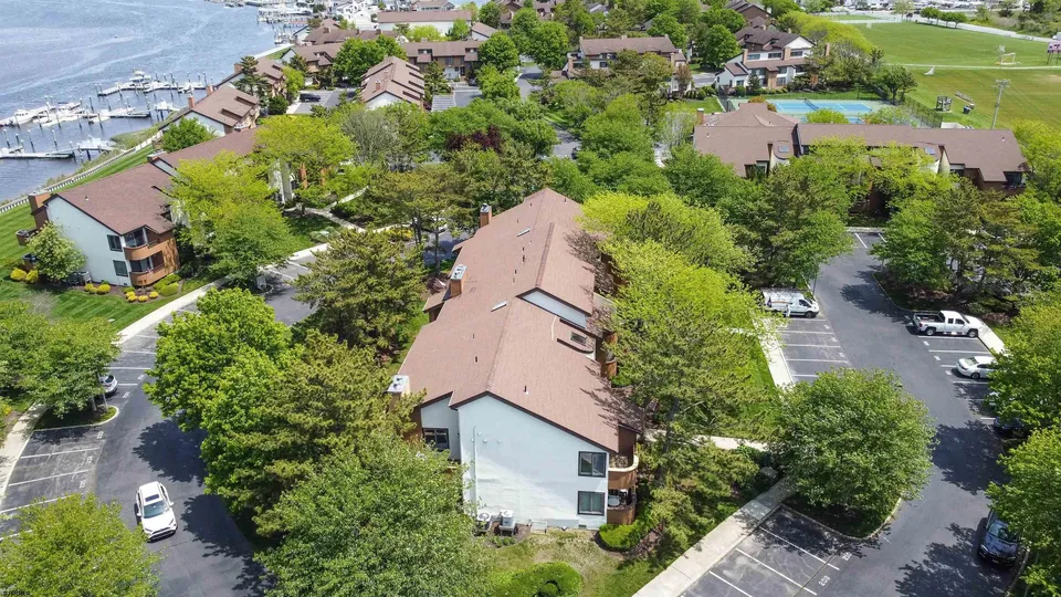 We see a white condo in Ocean City, NJ in the middle of a bunch of trees with a bay in view.
