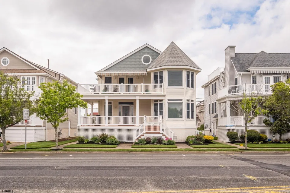 We see the front porch area of a beige house in Ocean City, NJ against a cloudy sky.