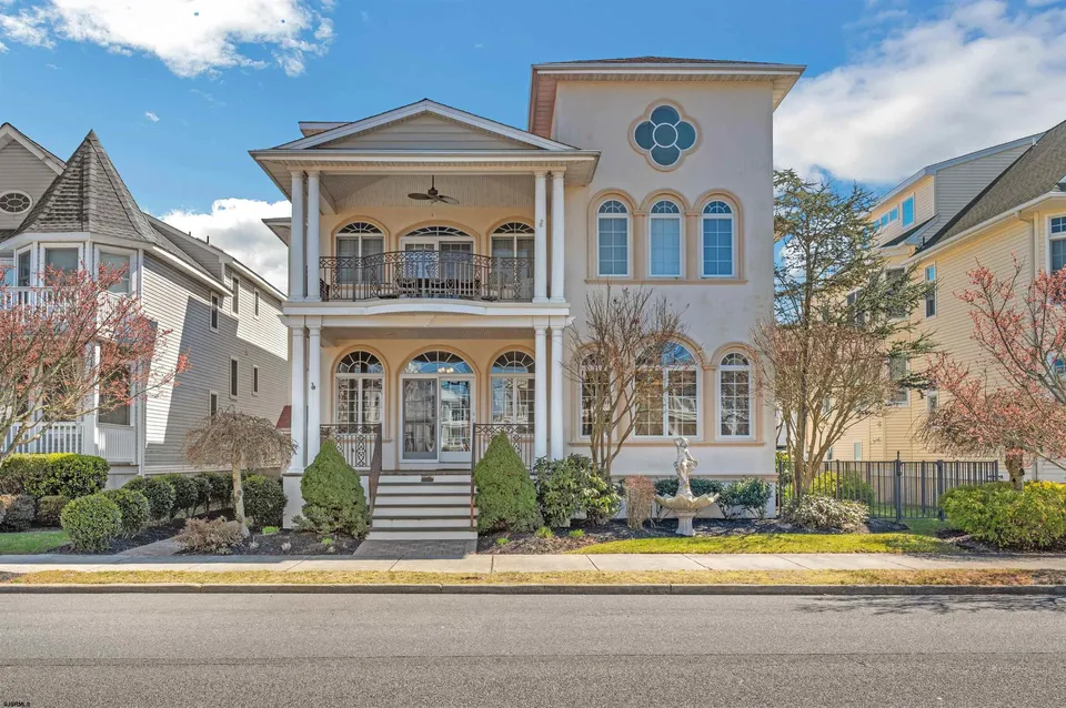 We see the front of a beige and white single-family home in Ocean City, NJ against a clear blue sky.