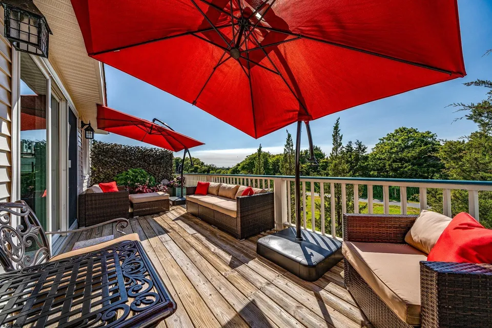 We see the back porch area of a home in Ocean City, NJ against a clear blue sky. Trees and other flora are in view as well.
