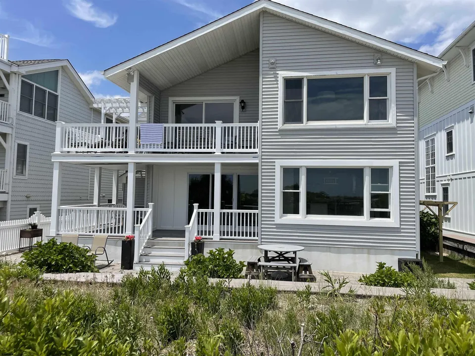 We see the front of a grey, two-story house in Ocean City, NJ against a clear blue sky.