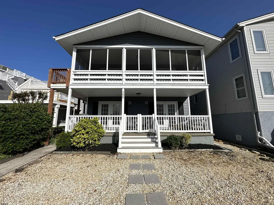 We see the front porch area of a white house in Ocean City, NJ against a clear blue sky.