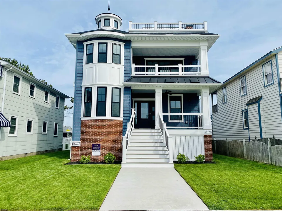 We see the front of a white and blue house in Ocean City, NJ against a clear blue sky.