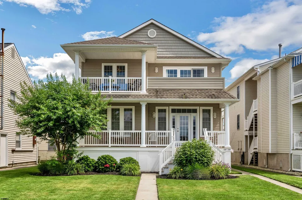 We see the front of a beige house in Ocean City, NJ against a clear blue sky.