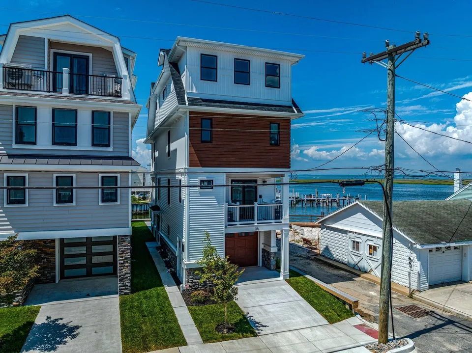 We see the front of a white and brown house in Ocean City, NJ against a clear blue sky.