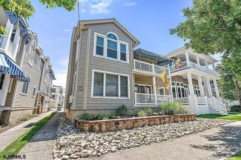 We see the front of a beige house in Ocean City, NJ against a clear blue sky.