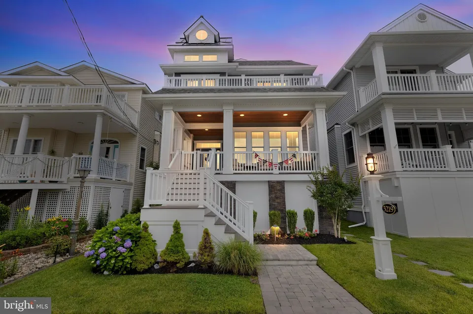 We see the front of a white and grey house in Ocean City, NJ at night.